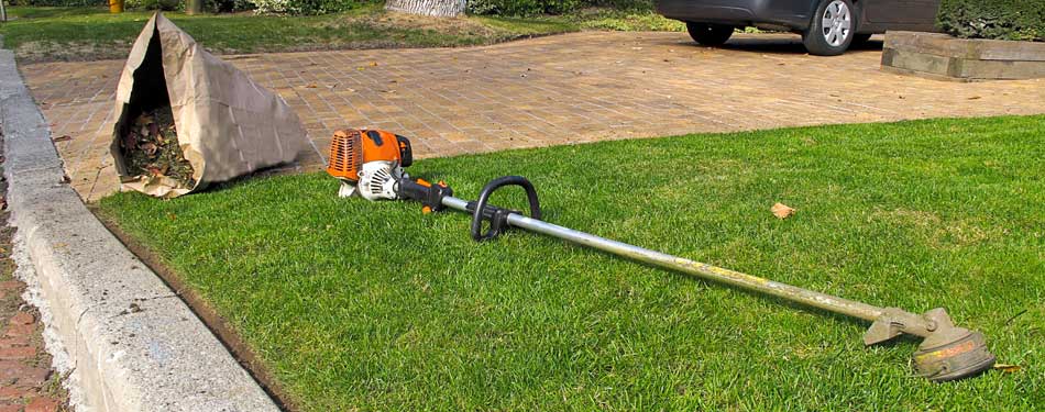 Nicely edged lawn with a string trimmer and a bag of landscaping debris at a home in Hanover, MI.